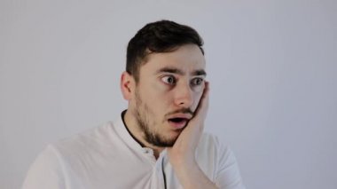  Şok olmuş genç bir adam kameraya bakar, elleri suratında şaşkın bir adam., 