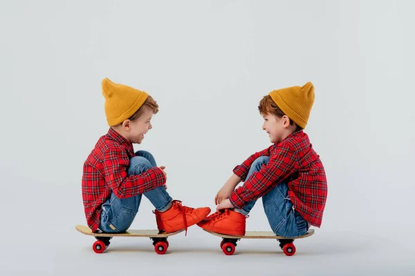 Щасливі хлопчики-близнюки сидять на скейтбордах в студії — стокове фото