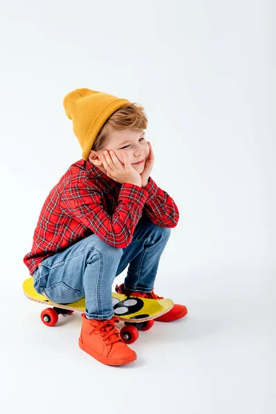 Маленький ребенок сидит на скейтборде, одетый в красную рубашку — стоковое фото