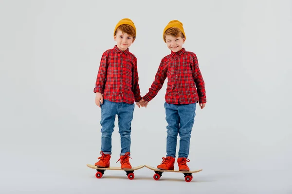 Twee kinderen houden elkaars hand vast, staan op skateboards — Stockfoto