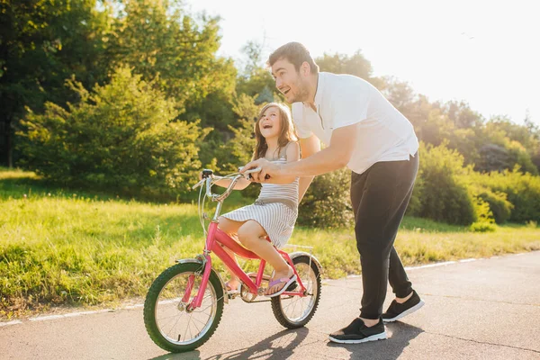 Happy father rejoices that her daughter learned to ride a bike,