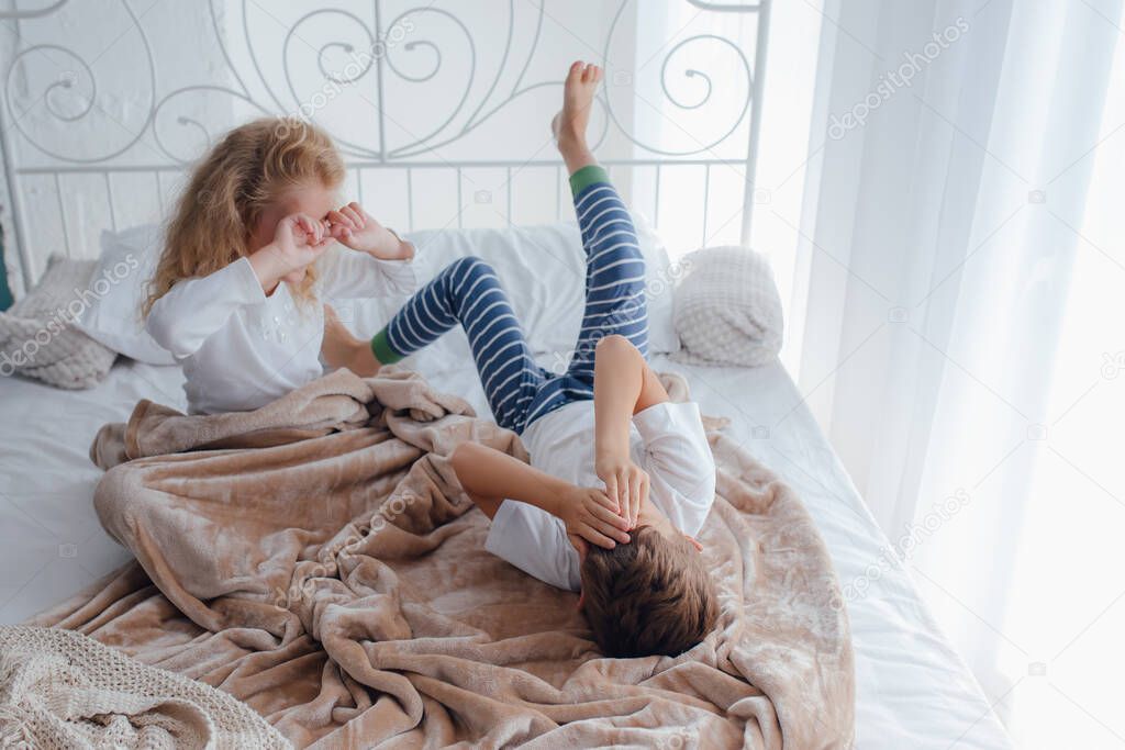 Little siblings waking up in cozy bed