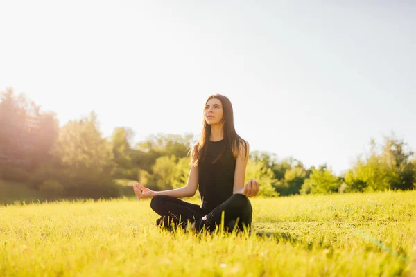 Frau meditiert im Gras sitzend und macht Yoga — Stockfoto