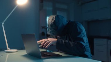 Karanlık bir evde, bilgisayar korsanı masada oturmuş zaferi kutluyor. Duyguları başarısından memnuniyet ve güven gösteriyor..