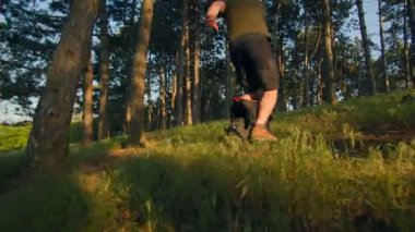 Elektrikli tek tekerlekli bisikletle ormandaki uzun otların arasından geçen bir adamın düşük açılı görüntüsü. Doğada taze ve eğlenceli bir off-road deneyimi..