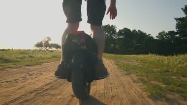 Gün batımında bir kır yolunda tek tekerlekli bisiklete binen bir adamın silüeti doğada huzurlu ve yüksek teknolojili bir yolculuğun keyfini çıkarırken tozu dumana katıyor..