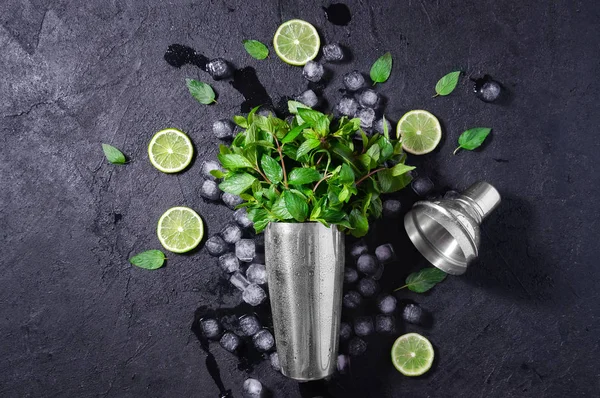 Chrome Bar Shaker With Lime, Mint and Ice on Dark Stone Table. Concept Of Cold Summer Drinks. Top View Flat Lay. Copy Space For Your Text — Stock Photo, Image