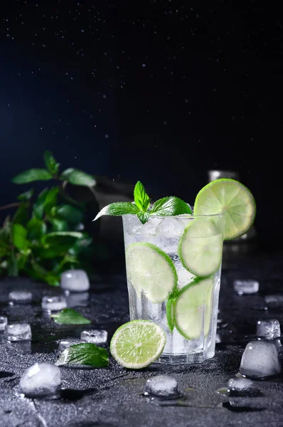 Коктейль Мохито или Лимонад с лаймом, мятой и льдом на тёмном фоне. Концепция свежих летних напитков — стоковое фото