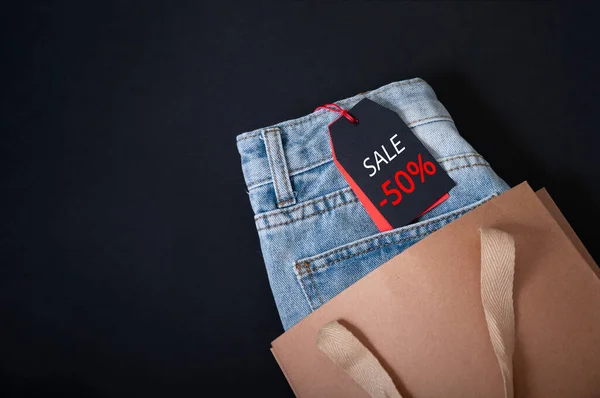 Black Friday Concept. Mock-up Tag Jeans and Paper Shopping Bag on Dark Background