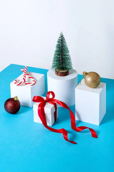 Creative Minimal Christmas Concept with Fir Tree, Gift Box, Ball and Candys on Different Geometrics Podium — Stock Photo, Image