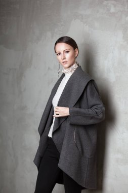 yüksek moda portre Studio gri Duvar beton sıva arka planda, kış sonbahar koleksiyonu genç zarif kadın açık gri ceket