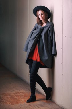 Boho hippi tarzı kadın Studio kırmızı elbise, siyah yuvarlak şapka giyen sıva gri duvara yakın kalıyor. Moda model poz