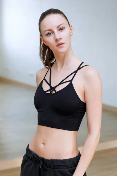 Žena představuje dělá cvičení ve fitness klubu, na sobě černé tričko s pruhy — Stock fotografie
