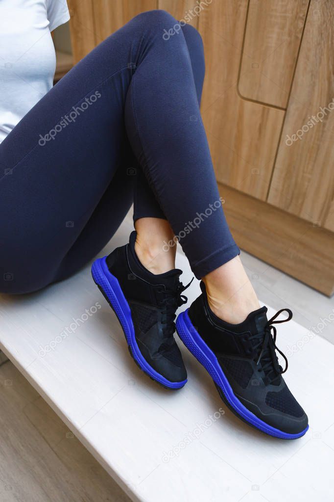close up of Woman wearing black sneakers on wooden floor background sitting on the bench in dressing room