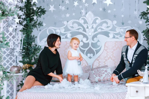 Navidad feliz familia de tres personas sentadas en la cama de fondo dormitorio blanco — Foto de Stock