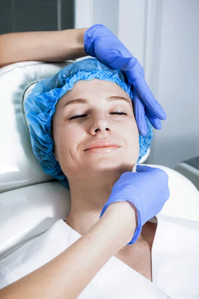 Cosmetólogo está aplicando crema con anestesia en la cara de los pacientes. Preparación de la piel para el procedimiento de biorevitalización — Foto de Stock