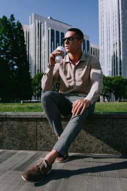 Tek kullanımlık kahvesi olan genç ve yakışıklı bir adam. Konsepti kaldır. Mola sırasında dışarıda oturmak.