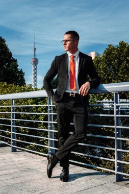 Siyah takım elbiseli, kırmızı kravatlı yakışıklı, seksi, orta yaşlı bir iş adamı bir iş yerinin önünde duruyor. İş adamının Portresi