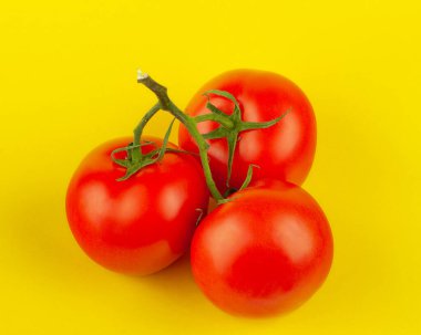Sarı arka planda üç kırmızı, lezzetli domates.