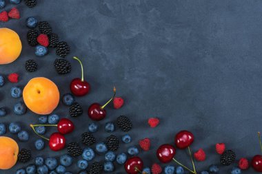 Böğürtlen, yaban mersini, ahududu, siyah beton arka plan üzerinde kiraz. Sağlıklı gıda