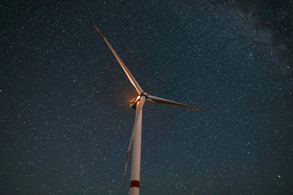 Wind turbine in the night at the stars background. Environment and renewable energy.