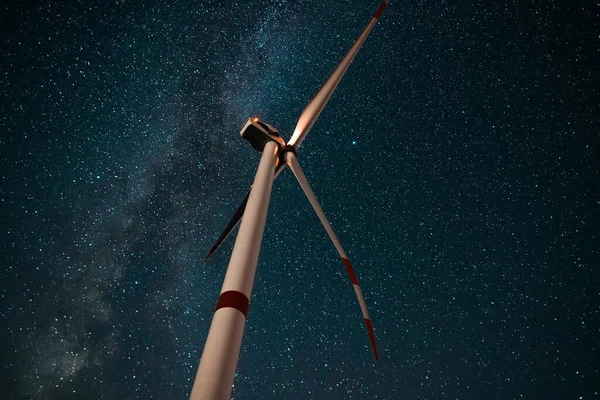 Wind turbine in the night at the stars background. Environment and renewable energy.