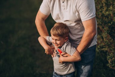 Baba ve oğul sahada oynuyorlar. Koşup eğleniyorlar..