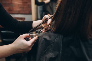 Usta kuaför bir kızın saçını makasla keser.