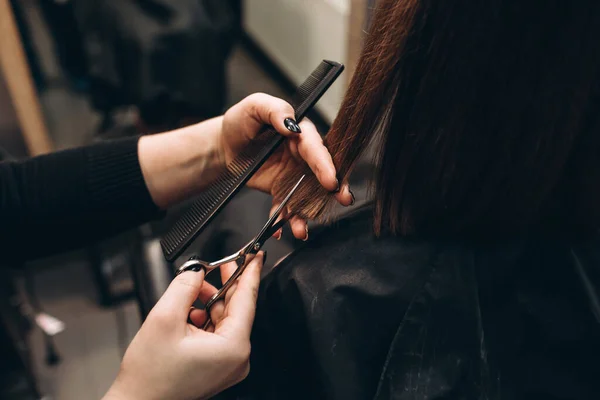 Master hairdresser cuts a girl\'s hair with scissors