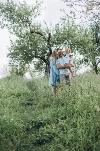 若い家族 娘は木のある庭で自然を楽しんでいます 楽しみ 抱き合って 一緒に幸せになる — ストック写真