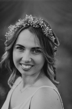 Kafasında çelenk olan güzel ve çekici bir kız gün batımında bir yaz tarlasında yürüyor.