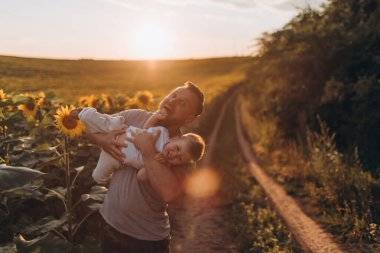 Küçük baba ve oğul yaz ayçiçeği tarlasında birlikte eğleniyorlar.