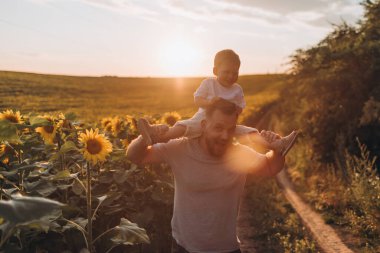 Küçük baba ve oğul yaz ayçiçeği tarlasında birlikte eğleniyorlar.