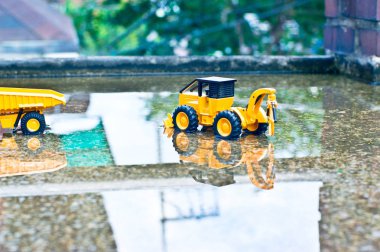 Kaldırımda tuğla sütunun yanında bir ekskavatör var..