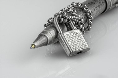 Yakın çekim tükenmez kalem metal bir zincir içinde beyaz arka plan üzerinde izole asma kilit ile kilitli. Basın özgürlüğü kısıtlayan kavramı. İroni konuşma özgürlüğü için insan haklarının