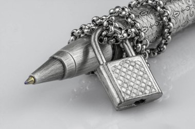 Yakın çekim tükenmez kalem metal bir zincir içinde beyaz arka plan üzerinde izole asma kilit ile kilitli. Basın özgürlüğü kısıtlayan kavramı. İroni konuşma özgürlüğü için insan haklarının