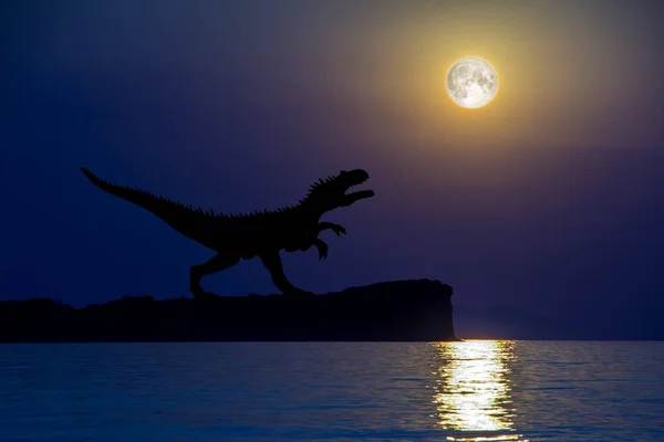 Terrible silhouette of tyrannosaurus standing on the cliff against the background of night sky with the full moon over the calm sea