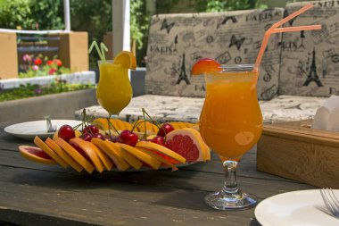 İki bardak suyu ve güneşli gün barda açık havada tabloda dilimlenmiş meyve ile plaka ile