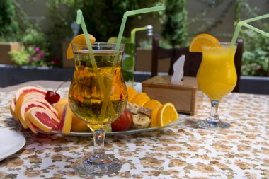 İki bardak suyu ve güneşli gün barda açık havada tabloda dilimlenmiş meyve ile plaka ile