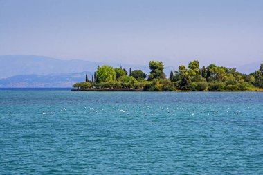 Güzel küçük bir ada: Korfu, Yunanistan kırık taş cliff ve mount üzerinde yeşil tropikal ağaçlar ile. Turkuaz rengi deniz mavi gökyüzü ile
