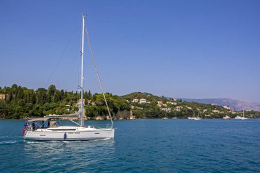 Beyaz lüks yat yelken önünde güzel, yeşil ağaçlar Corfu Island, Yunanistan ile kaplı yelken açtı