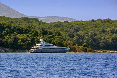 Mavi deniz Corfu Island, Yunanistan koyu arka plan üzerinde yeşil ağaçlar ile modern yat demirleyen
