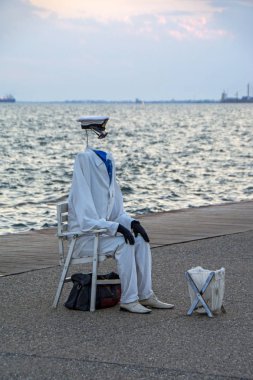 Thessaloniki, Yunanistan için arka plan üzerinde denize gün batımı ile seafront, görünmez adam gibi bir sokak sanatçı erkek giyimi