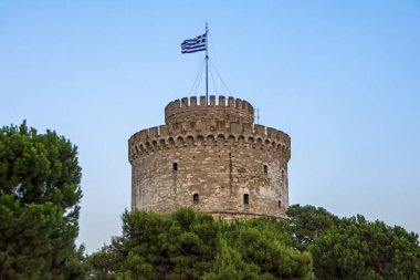 Beyaz Kule Selanik üst mavi gökyüzü arka planda Orta Makedonya, Yunanistan ile yeşil kozalaklı ağaçlar üzerinde Yunan bayrağı ile