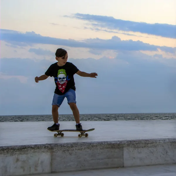 希腊塞萨洛尼基 2018年7月6日 一名年轻的滑板运动员在日落时在有海景的大理石表面上做滑板把戏 — 图库照片