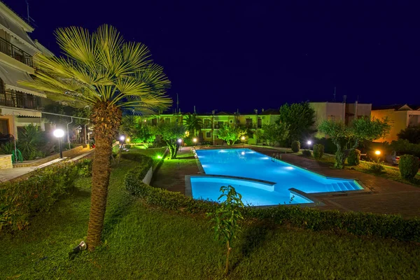Chalkidiki, Yunanistan - 08 Temmuz 2018: Güzel gece sahne lüks evler ve Halkidikya, Yunanistan için yeşil ağaçlar arasında ışıklı mavi yüzme havuzlu