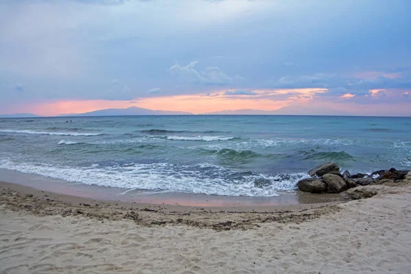 劇的な曇り空と前景に背景と砂浜のビーチに山と青い海に夕日 — ストック写真