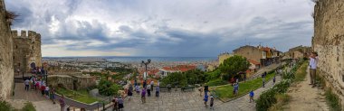 Thessaloniki, Yunanistan - 09 Temmuz 2018: Mavi deniz ve arka plan üzerinde dramatik gökyüzü için büyük panorama Selanik. Trigoniou Kulesi (solda) ve Anna Palaiologos kapı Trigonio (sağda) görüntüleyin. Turistler fotoğraf yapar