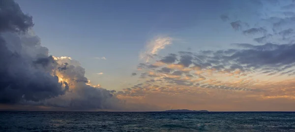 日の出劇的な雲の下のネイビー ブルーの海の波と水平線上のコルフ島の神秘的なシルエットの大パノラマ ギリシャのエリクッサ島からの眺め — ストック写真