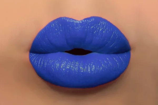 Human kiss lips with glamorous glossy blue lipstick on the face of an attractive beautiful woman as a beauty and health concept pertaining to cosmetics and female business fashion